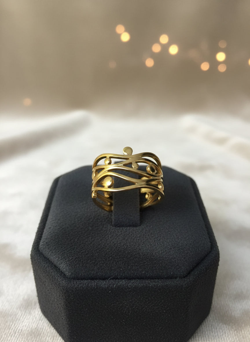 Elegant gold abstract ring featuring intertwined design and spherical accents, showcased on a black display.