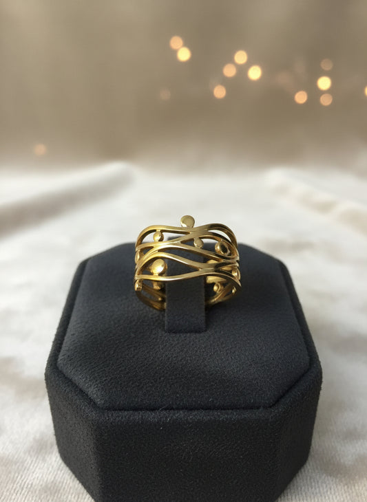 Elegant gold abstract ring featuring intertwined design and spherical accents, showcased on a black display.