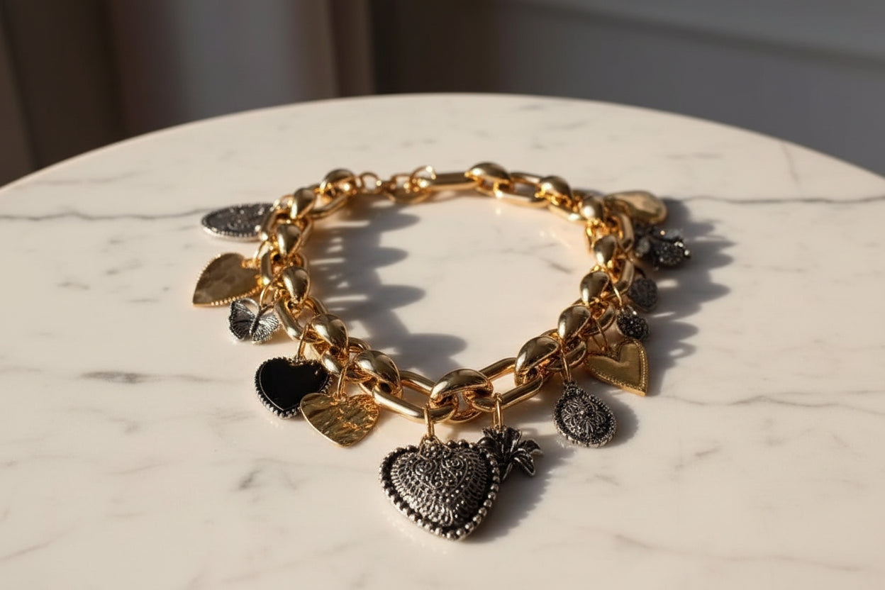 Gold chain bracelet featuring heart charms in black and silver, perfect for trendy accessorizing.