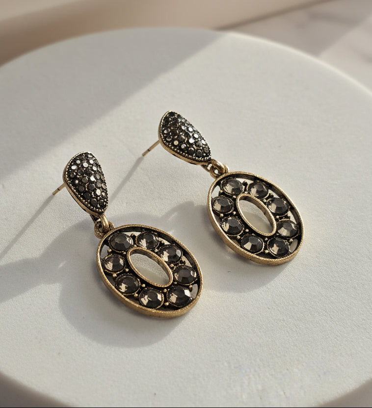 Elegant gold and black earrings with oval design and sparkly rhinestones, perfect for special occasions.