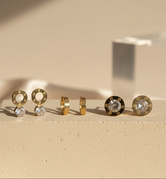 Elegant gold earrings set with clear crystals, featuring hoop and stud designs for versatile styles.