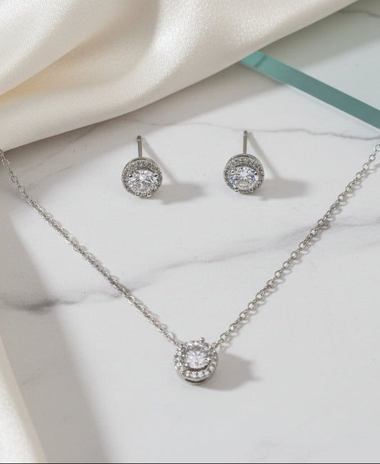 Silver necklace and stud earrings set with sparkling clear gemstones, elegant jewelry for special occasions.