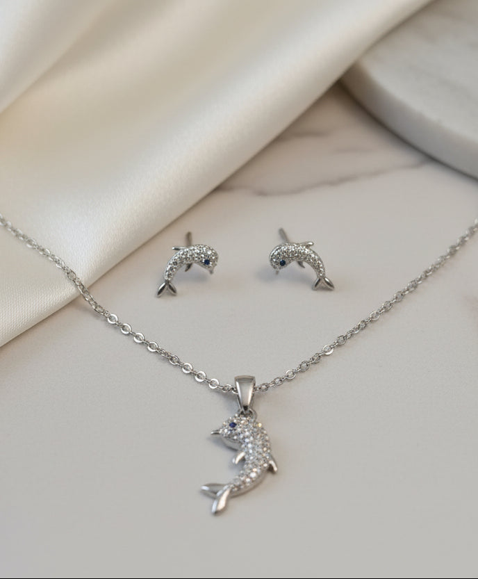 Silver dolphin jewelry set with sparkling accents, includes necklace and earrings.