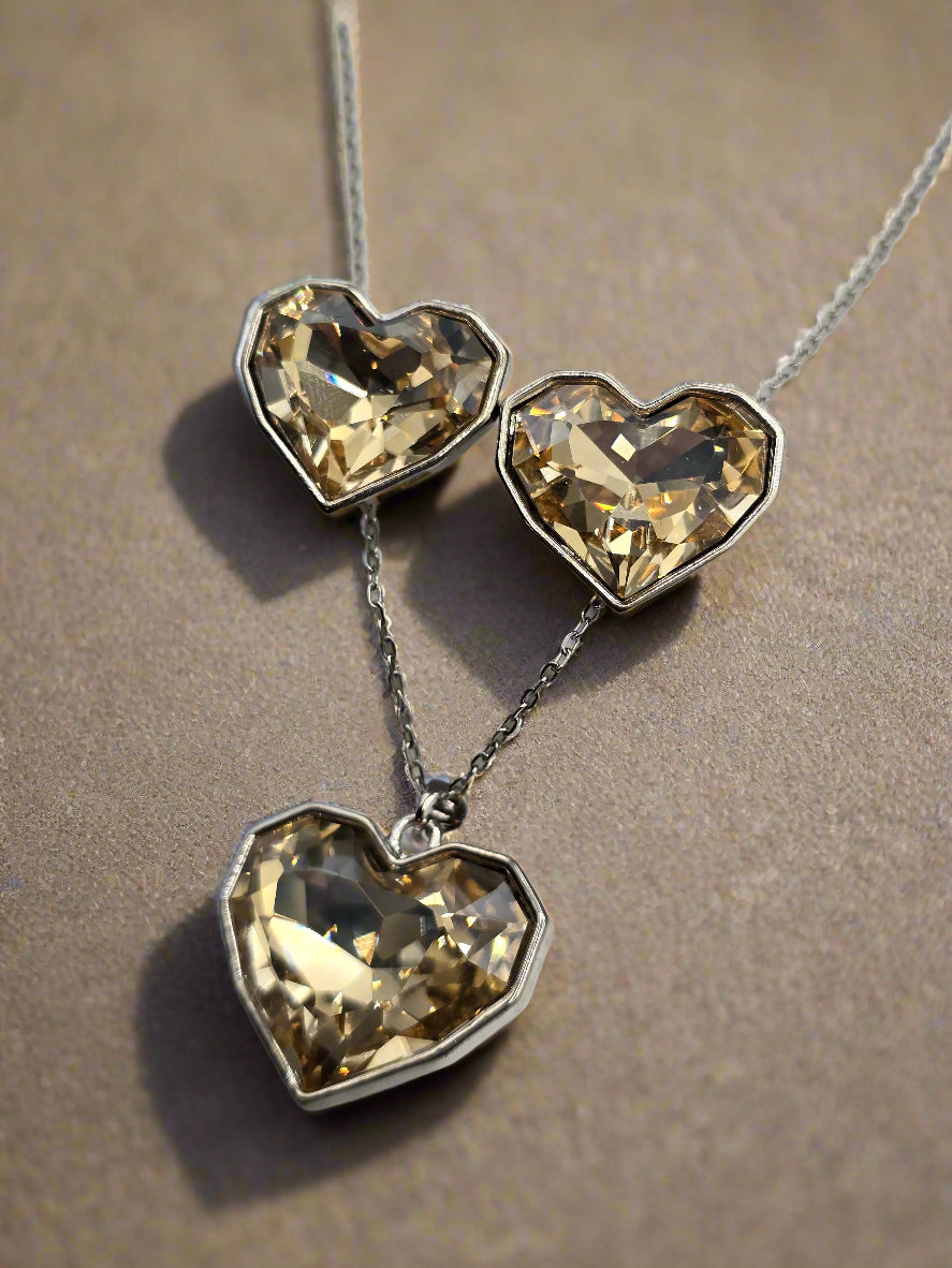 Silver heart-shaped necklace and earrings set with golden crystals, perfect for romantic occasions.