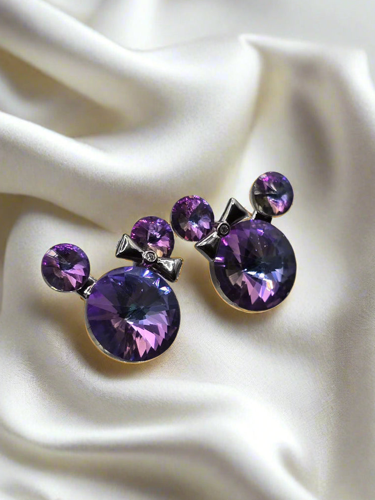 Purple crystal earrings with bow design, featuring large round stones and silver accents.