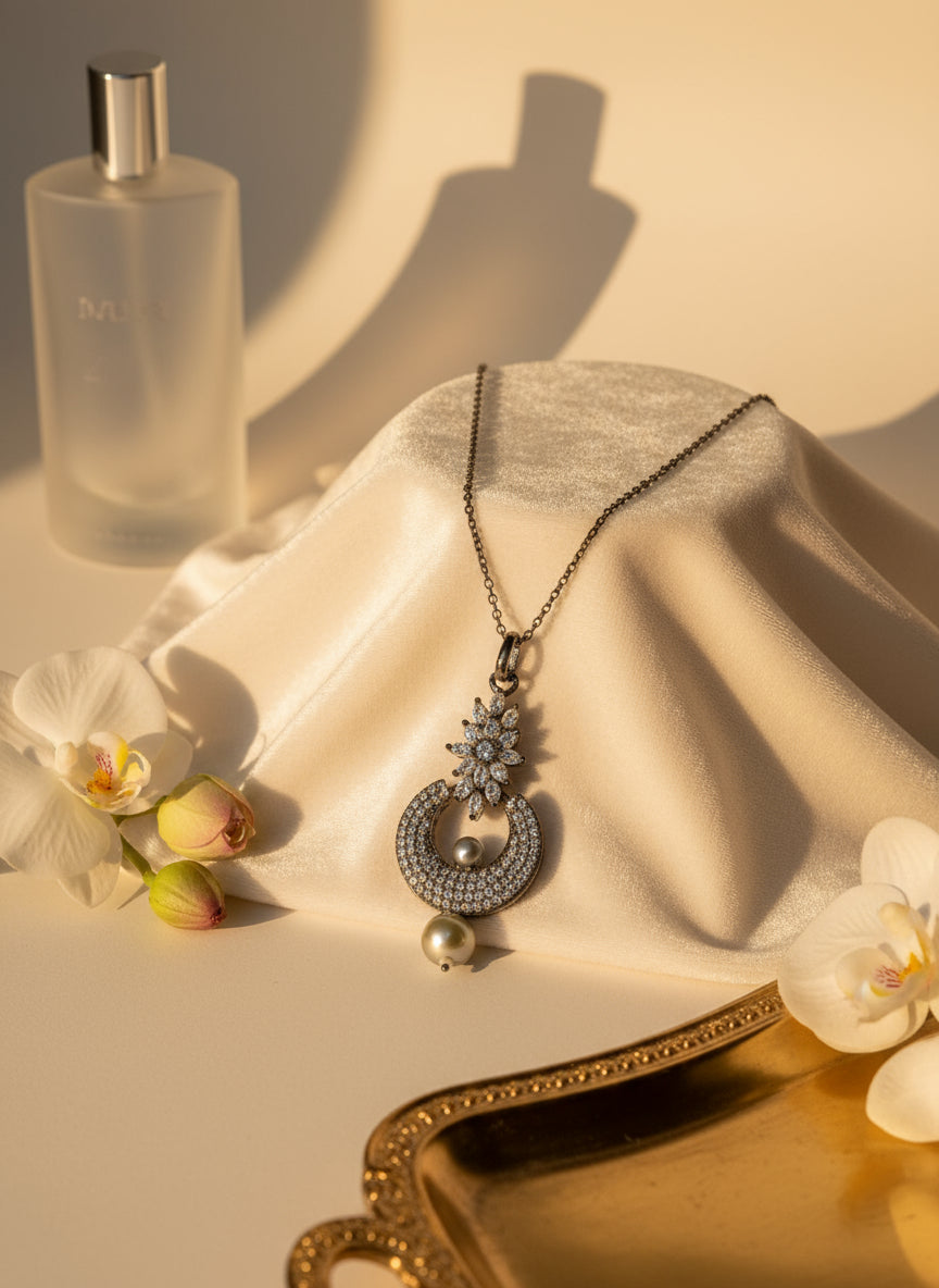 Elegant silver necklace with sparkling pendant and pearls, surrounded by flowers and a perfume bottle.