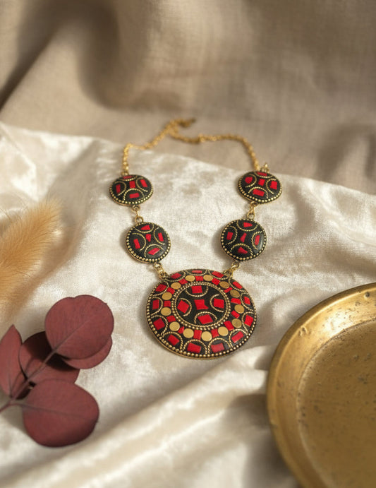 Handcrafted statement necklace with red and black floral design, gold chain, and unique pendant.