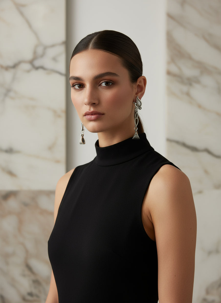 Elegant silver drop earrings with intricate designs, styled on a model wearing a black sleeveless top.
