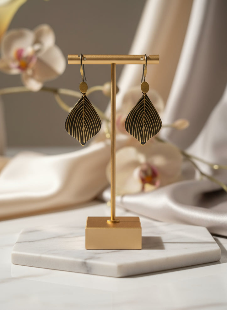Stylish gold leaf earrings on display stand, featuring intricate design and elegant silhouette.