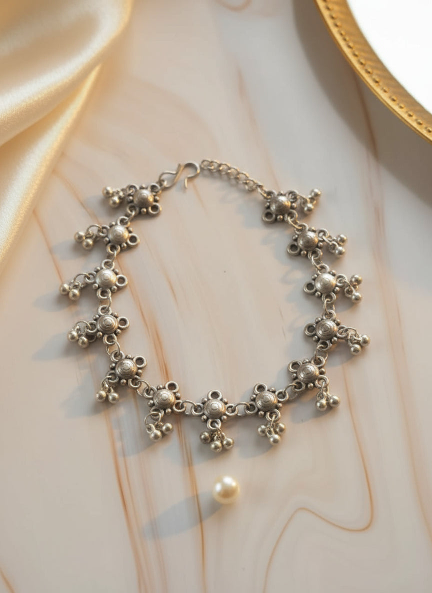 Silver statement bracelet with decorative metal charms and a lobster clasp closure.