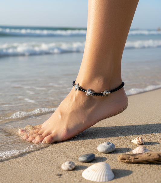 Black beaded anklet with silver turtle charms, stylish beach accessory for summer fashion.