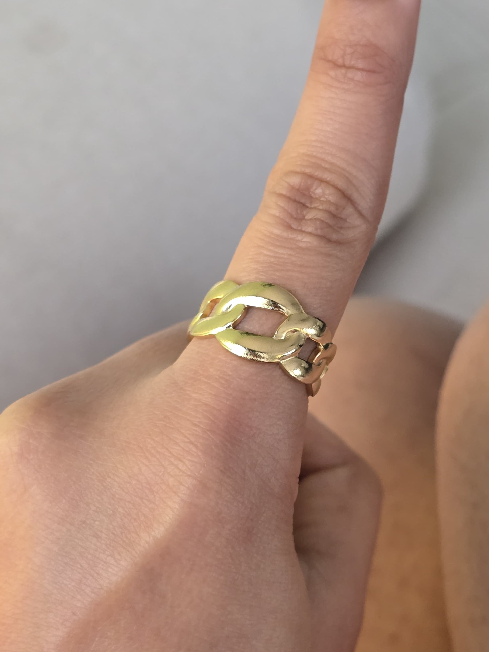 Gold chain link ring on a finger, stylish design, perfect for everyday wear or special occasions.