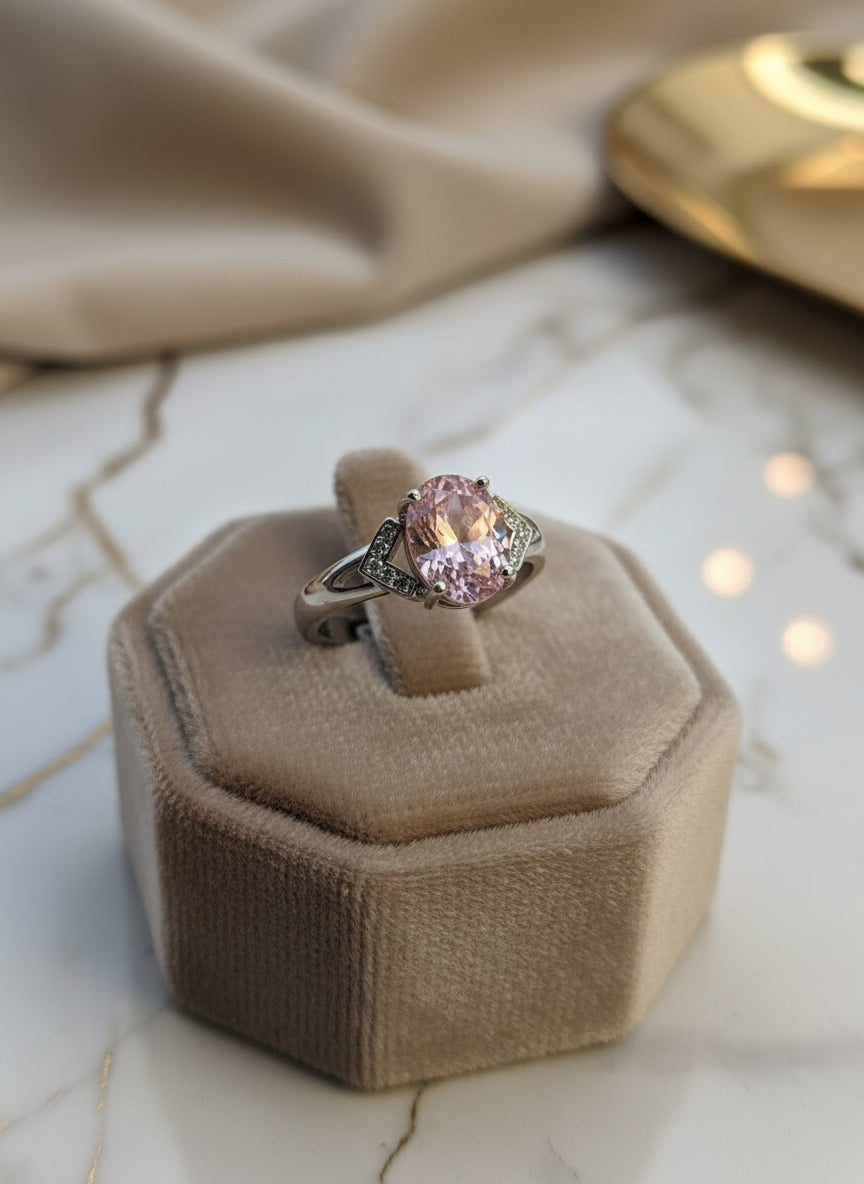 Elegant silver ring featuring a large pink gemstone and detailed accents, presented on a stylish display.