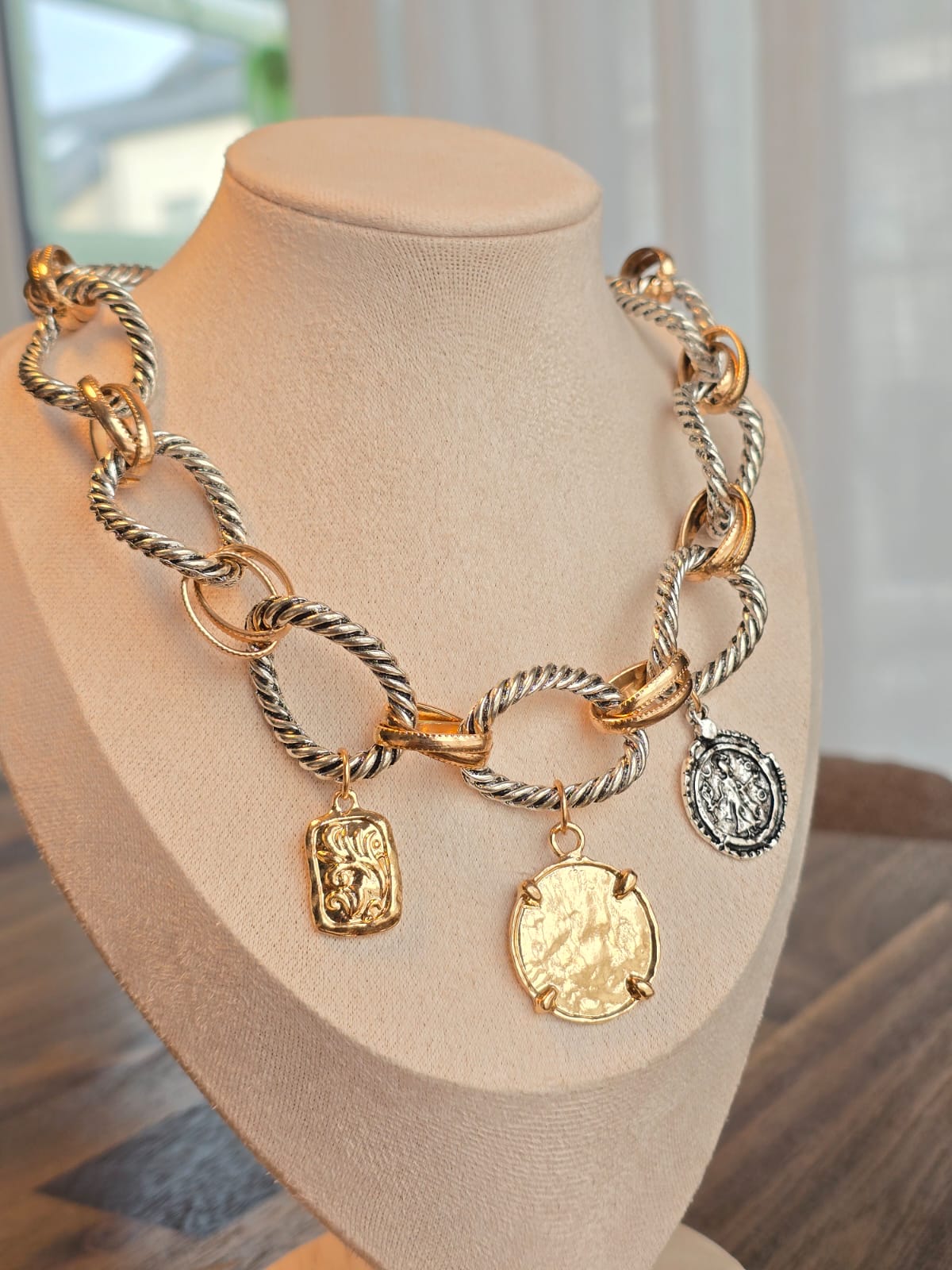 Stylish gold and silver chunky necklace with decorative pendants, made of metal and rope chain.