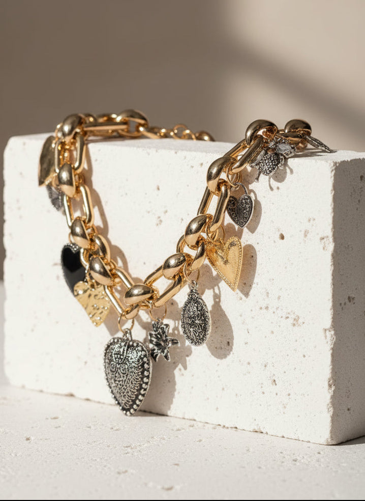 Chunky gold chain bracelet with heart charms in silver and black, stylish and unique jewelry piece.
