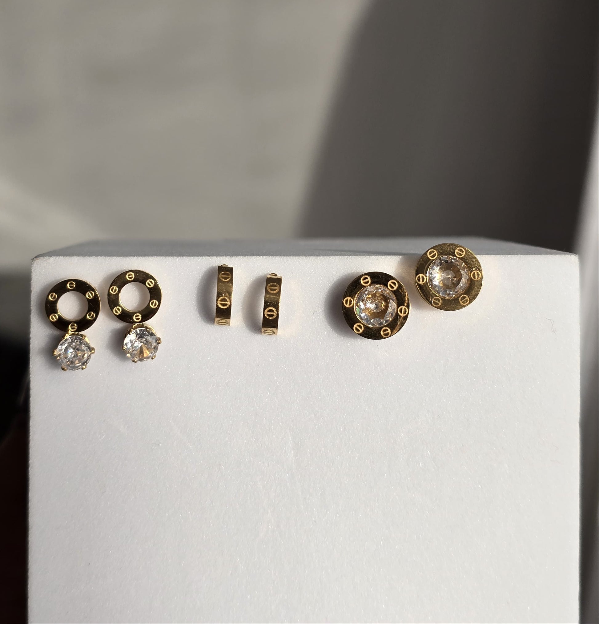 Elegant gold earrings set featuring round and stud designs with sparkling clear crystals.