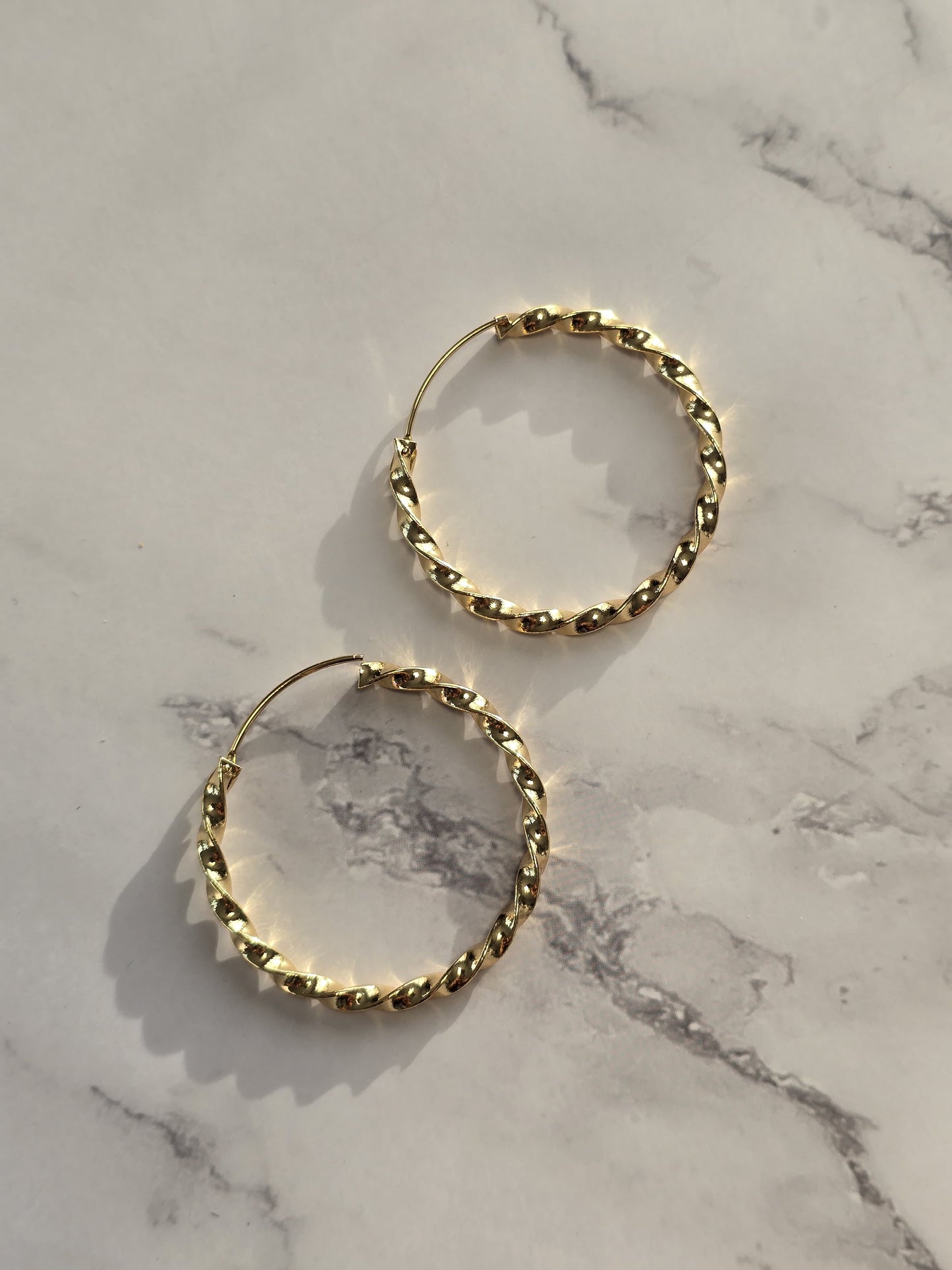 Gold twisted hoop earrings, trendy design, lightweight metal, perfect for casual or formal occasions.