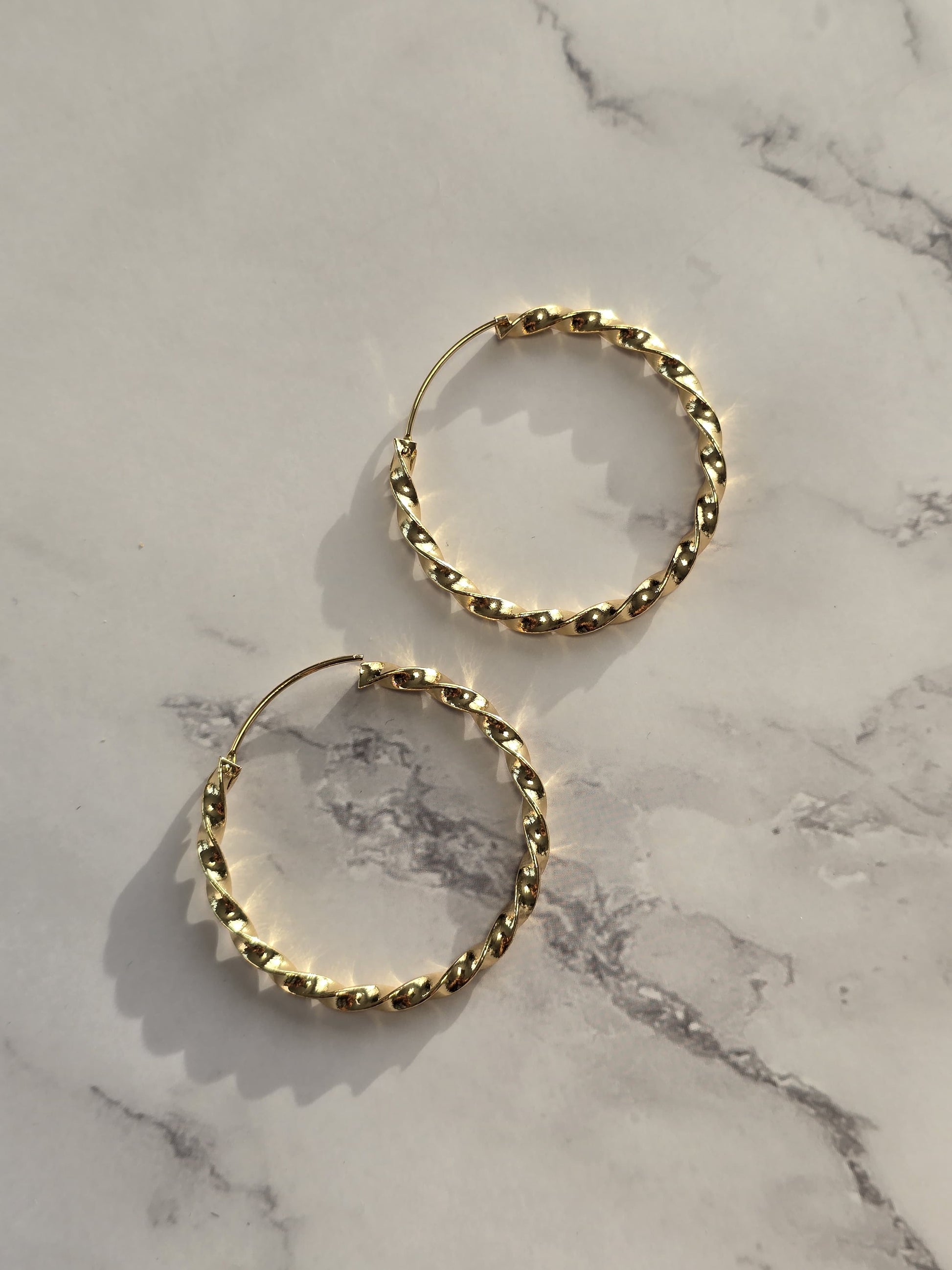 Gold twisted hoop earrings, trendy design, lightweight metal, perfect for casual or formal occasions.
