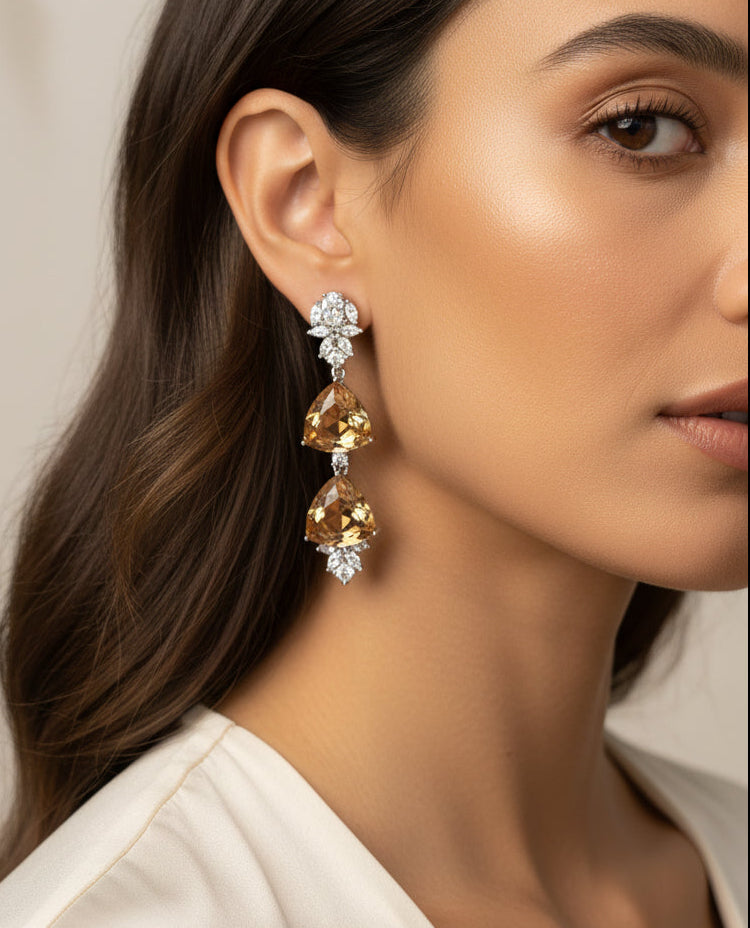 Elegant gold and crystal drop earrings featuring a geometric design and sparkling embellishments.