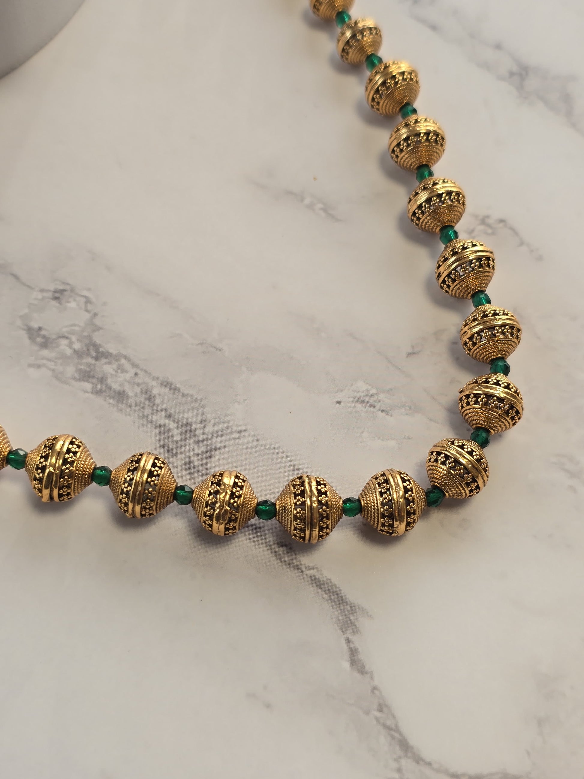 Elegant gold beaded necklace with green accents, featuring intricate patterns and vintage design.