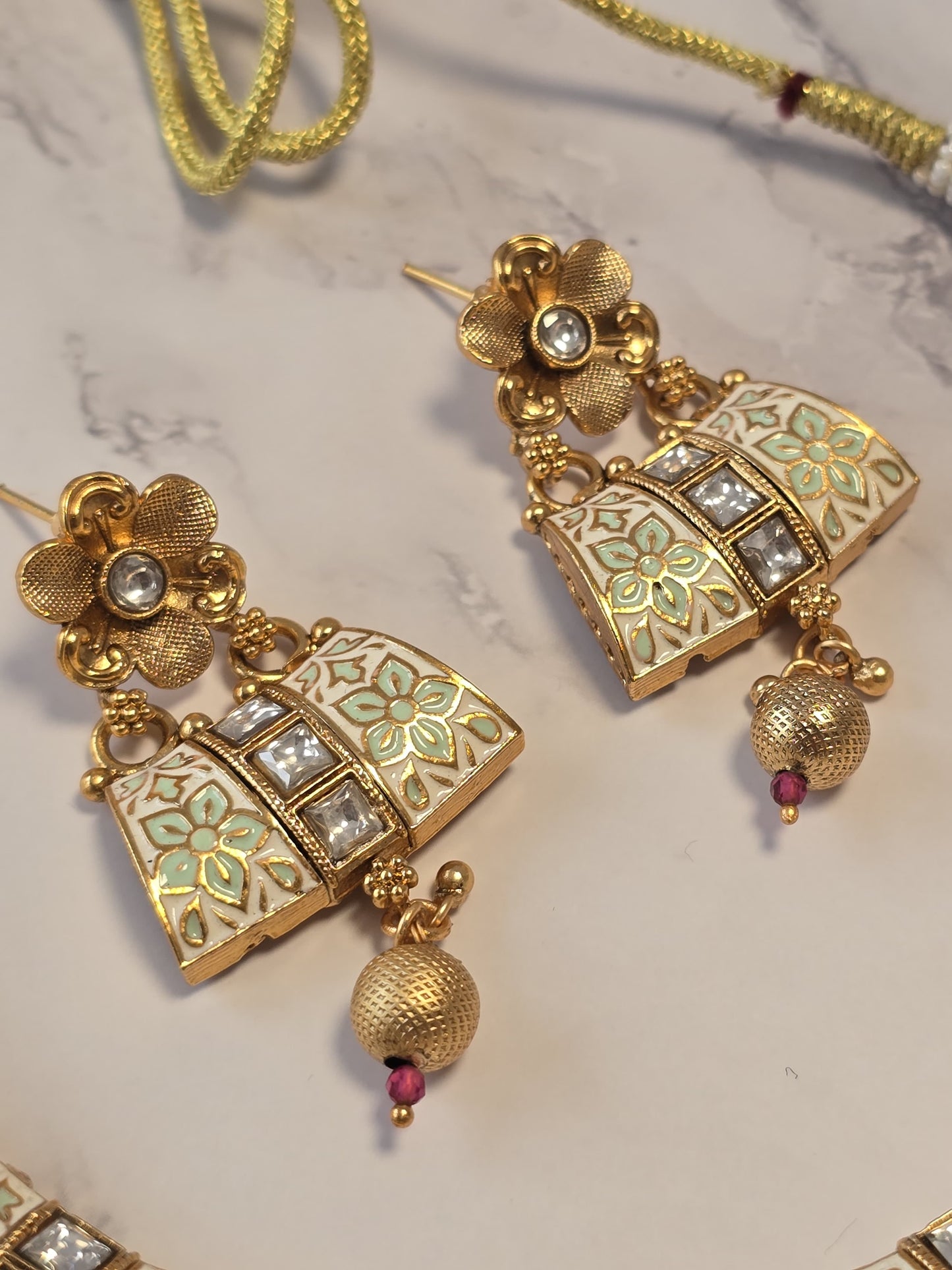 Gold vintage-style earrings with floral design, enamel accents, and sparkling gems.