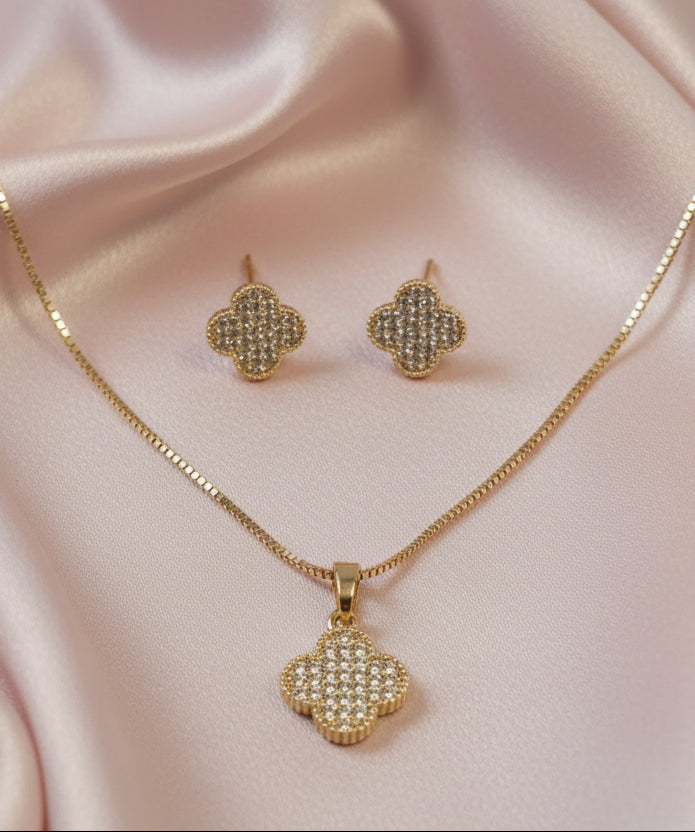 Gold jewelry set featuring a clover pendant necklace and matching earrings with sparkling details.