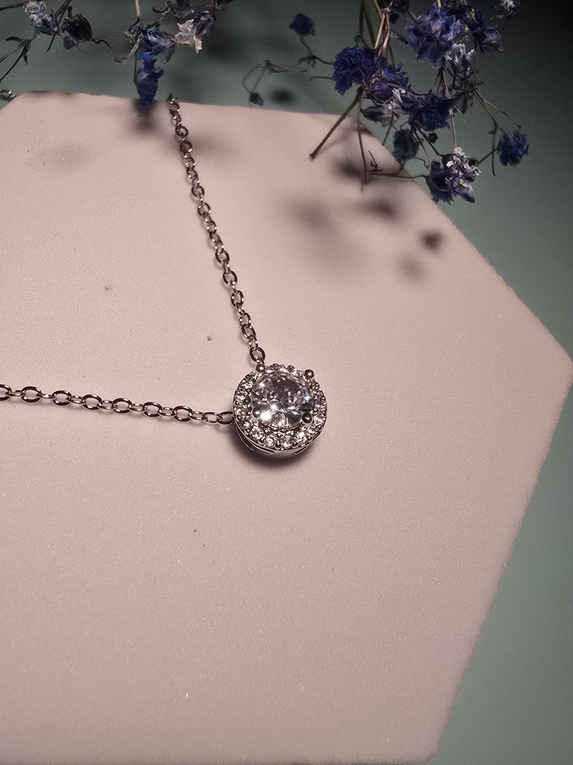 Silver pendant necklace with a circular clear gem and sparkling halo accents, perfect for elegant occasions.