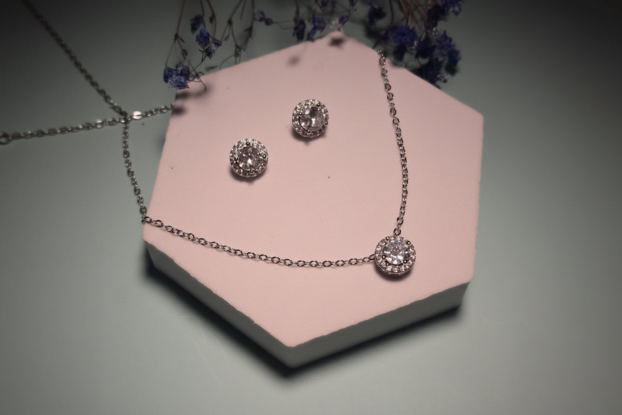 Silver jewelry set featuring a necklace and stud earrings with sparkling round crystals.