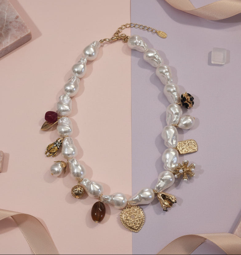 Elegant pearl necklace with gold charms, featuring unique shapes and a mix of colors.