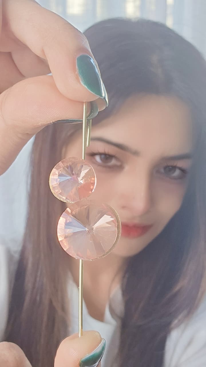 Elegant pink crystal earrings on a gold pin, showcasing sparkling round cuts and modern design.