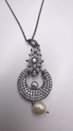Elegant silver pendant necklace featuring rhinestones and a pearl drop detail.